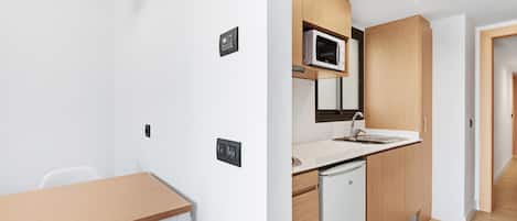 A modern kitchen with a microwave, sink, and wooden cabinets.