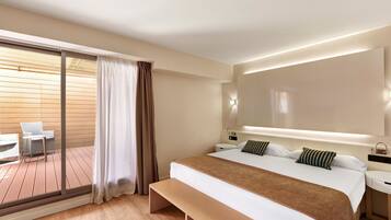 Una habitación de hotel moderna con una cama grande, un banco, un escritorio y un balcón con mesa y sillas.