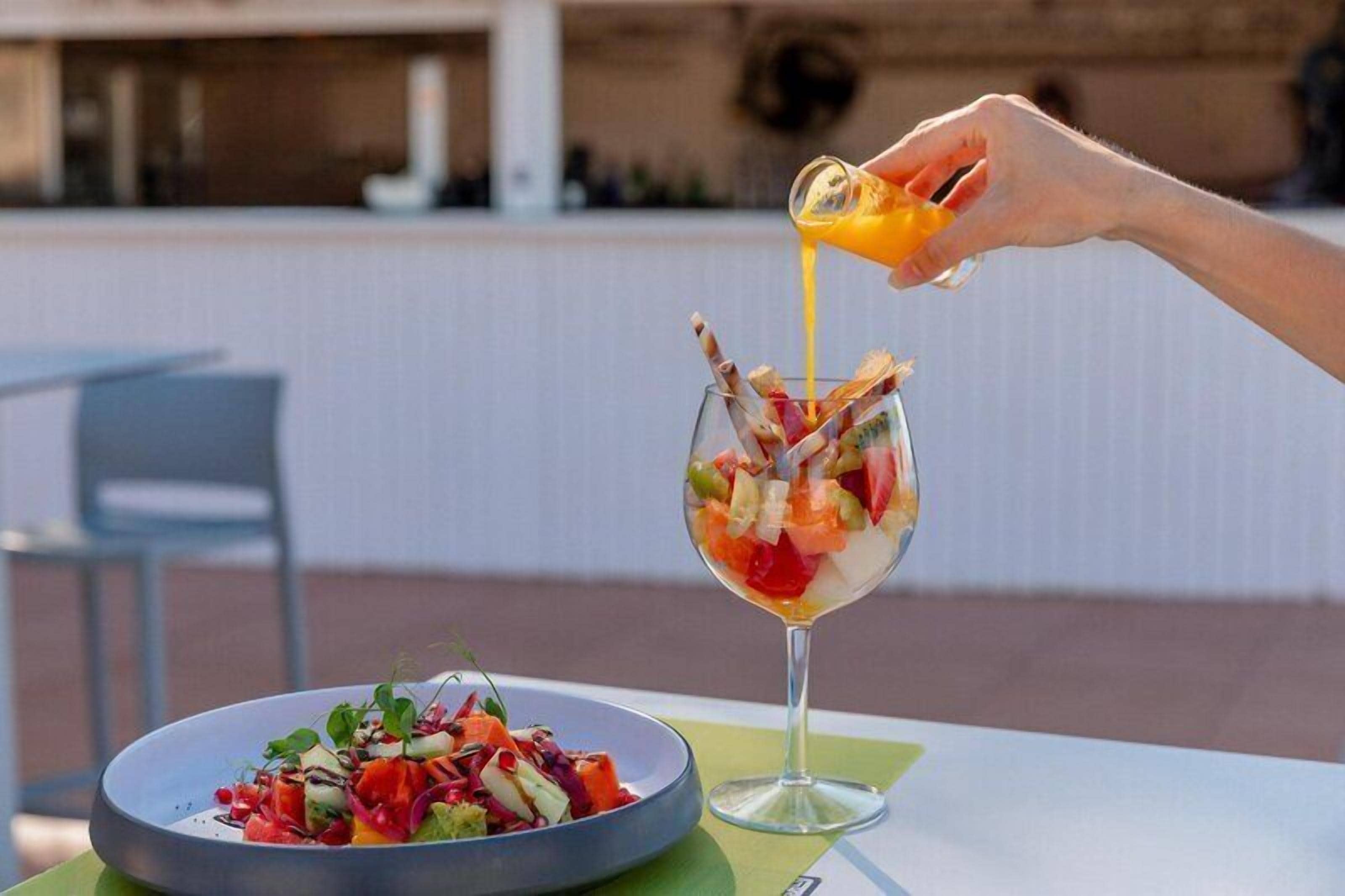 A dining table with a salad and a glass of orange juice.