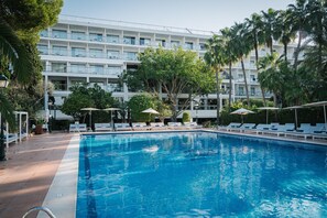 Alberca techada, alberca al aire libre y sombrillas en la alberca