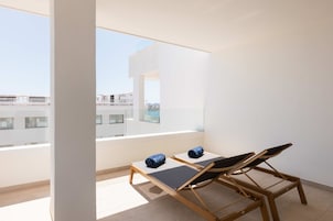 Un balcón con dos sillones, una mesita y vistas a edificios.