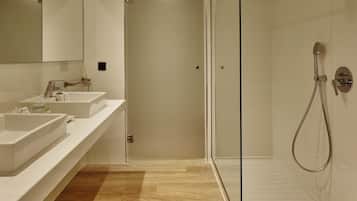 A modern bathroom with a glass-enclosed shower, two sinks, and a wooden floor.