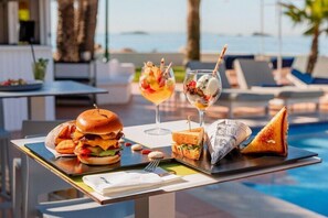 A dining table with a burger, sandwiches, a glass of iced tea, and a cocktail. - Hotel THB Los Molinos - Adults Only (Ibiza Town)
