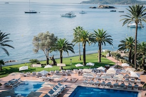 Área da piscina com espreguiçadeiras e guarda-sóis, com vista para uma marina com barcos.