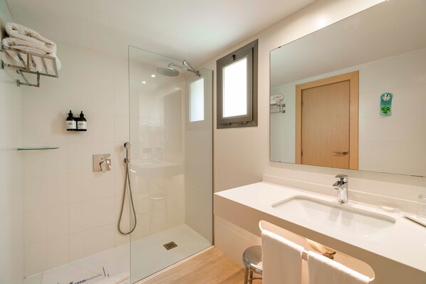 A modern bathroom with a glass-enclosed shower, a large mirror, and a white sink.