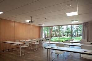 A classroom with rows of desks and chairs, large windows, and a view of a garden. - Hotel THB Los Molinos - Adults Only (Ibiza Town)