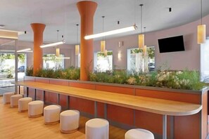 A reception area with a long counter, multiple seating options, and a TV mounted on the wall. - B&B Hotel Figueres  (Figueres)