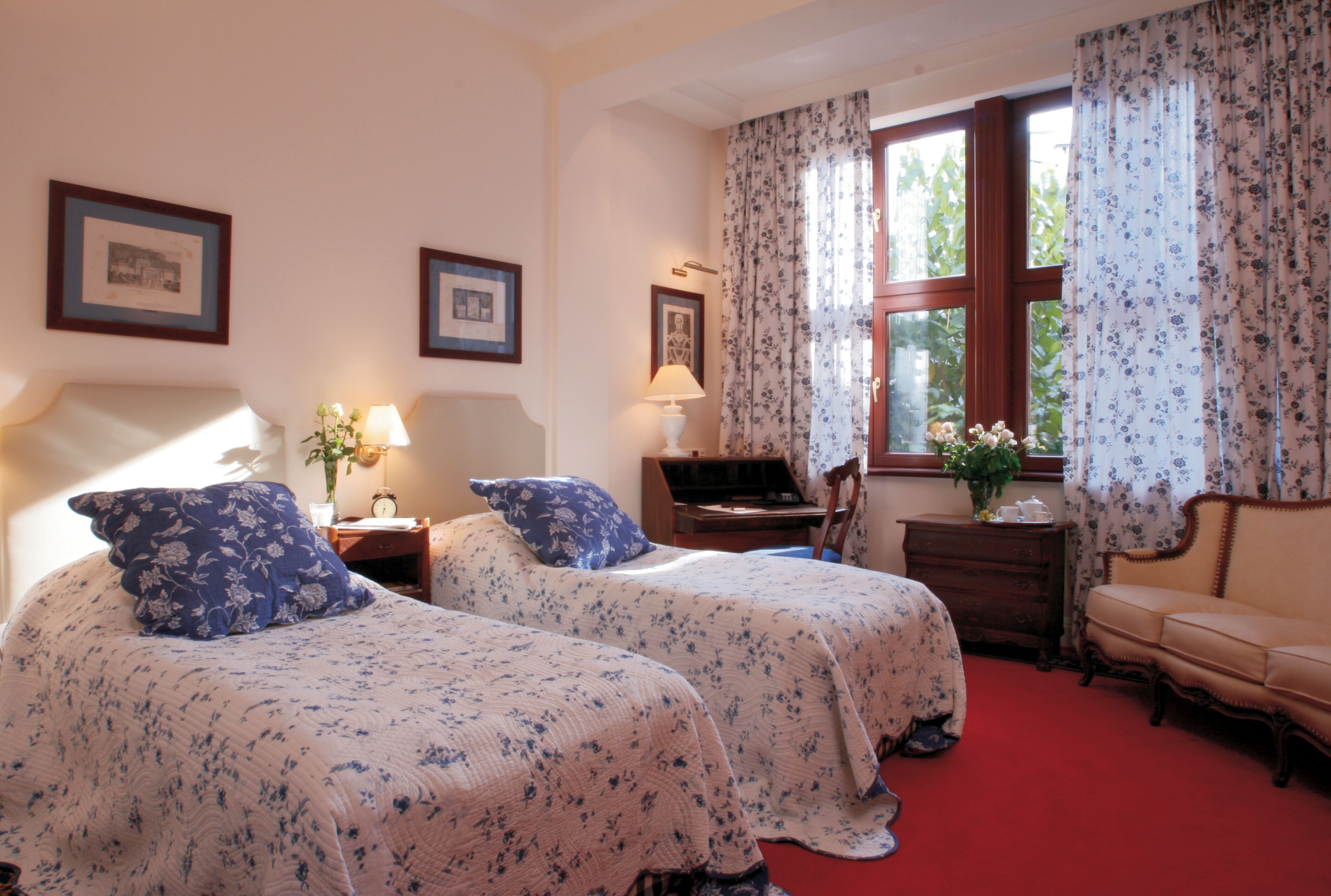 Une chambre avec deux lits, un bureau, une chaise et une fenêtre avec des rideaux.
