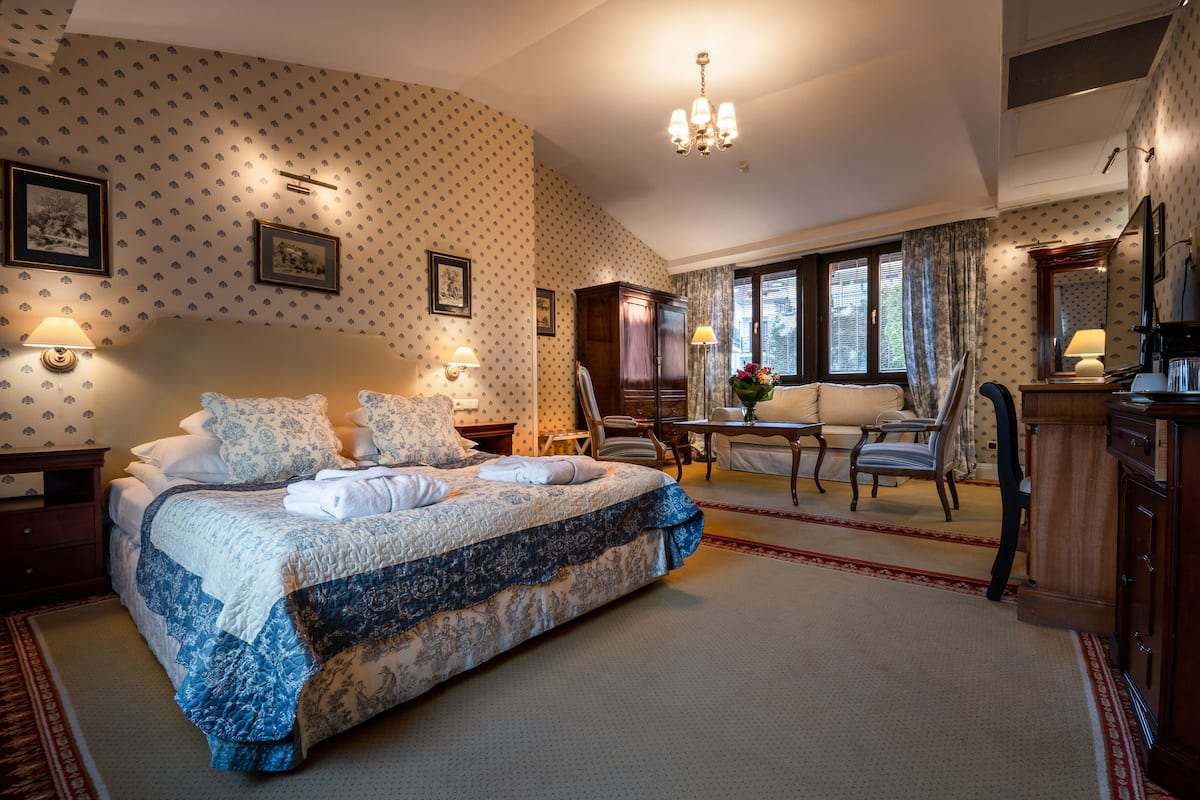 A hotel room with a large bed, a desk, a chair, and a dresser.