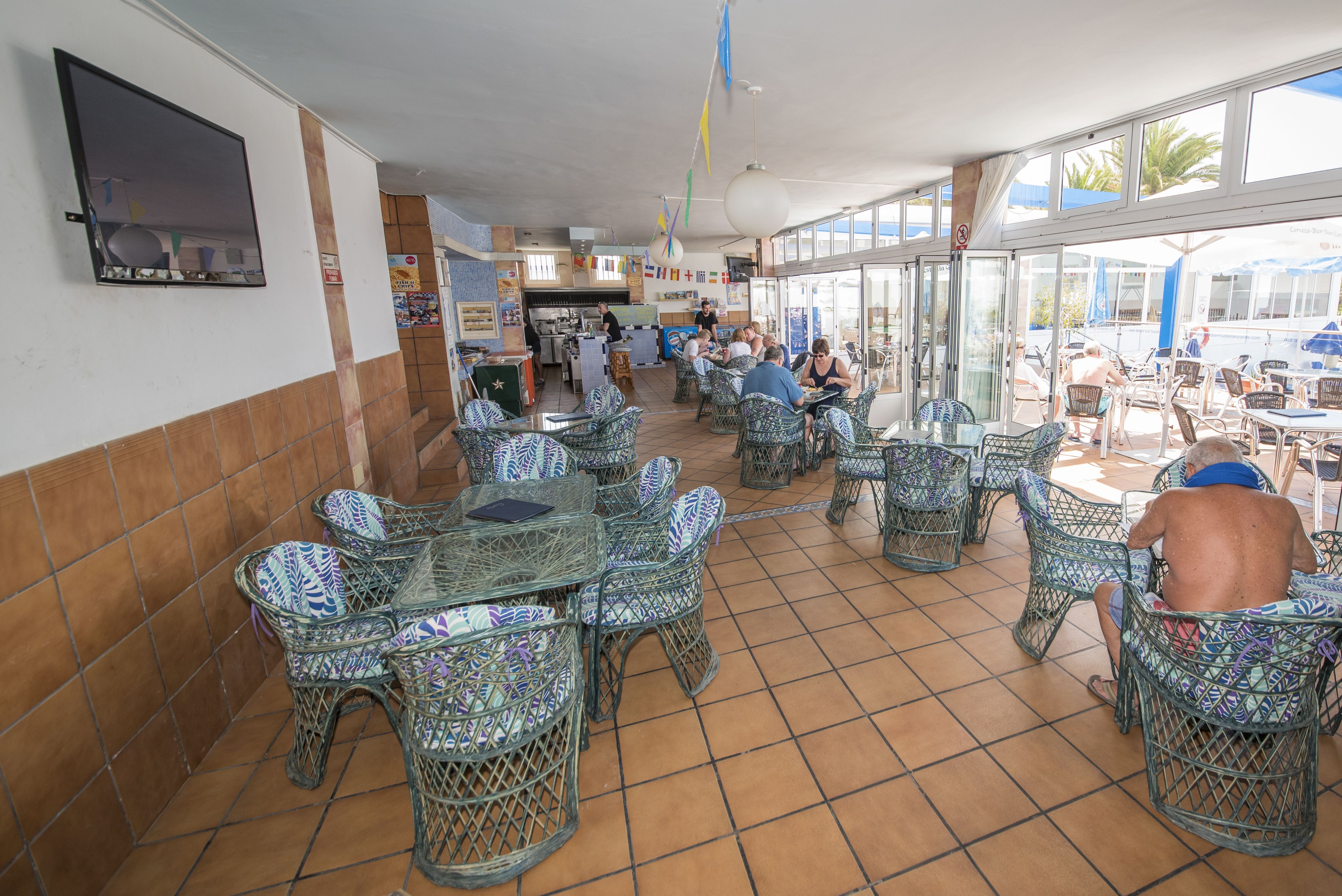 A restaurant with wicker furniture and tiled floors.