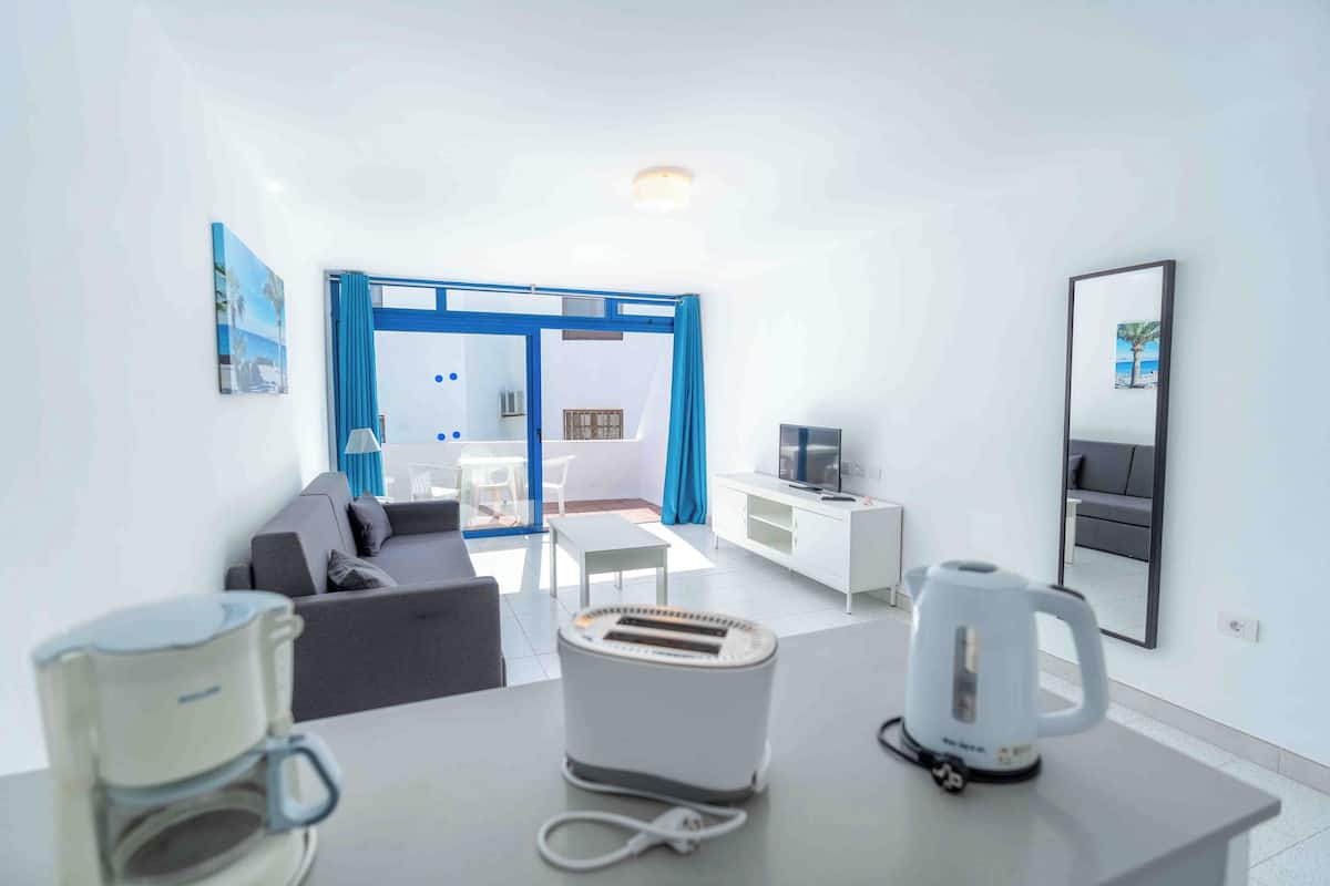 Una habitación de hotel moderna con sofá, mesa de centro, televisor, hervidor de agua y tostadora.