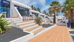 Un resort con edificios blancos, puertas azules y un camino empedrado.