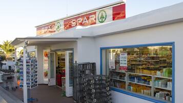 Un épicerie dont l’entrée est bien visible, avec des chariots de courses et des étagères remplies de produits.