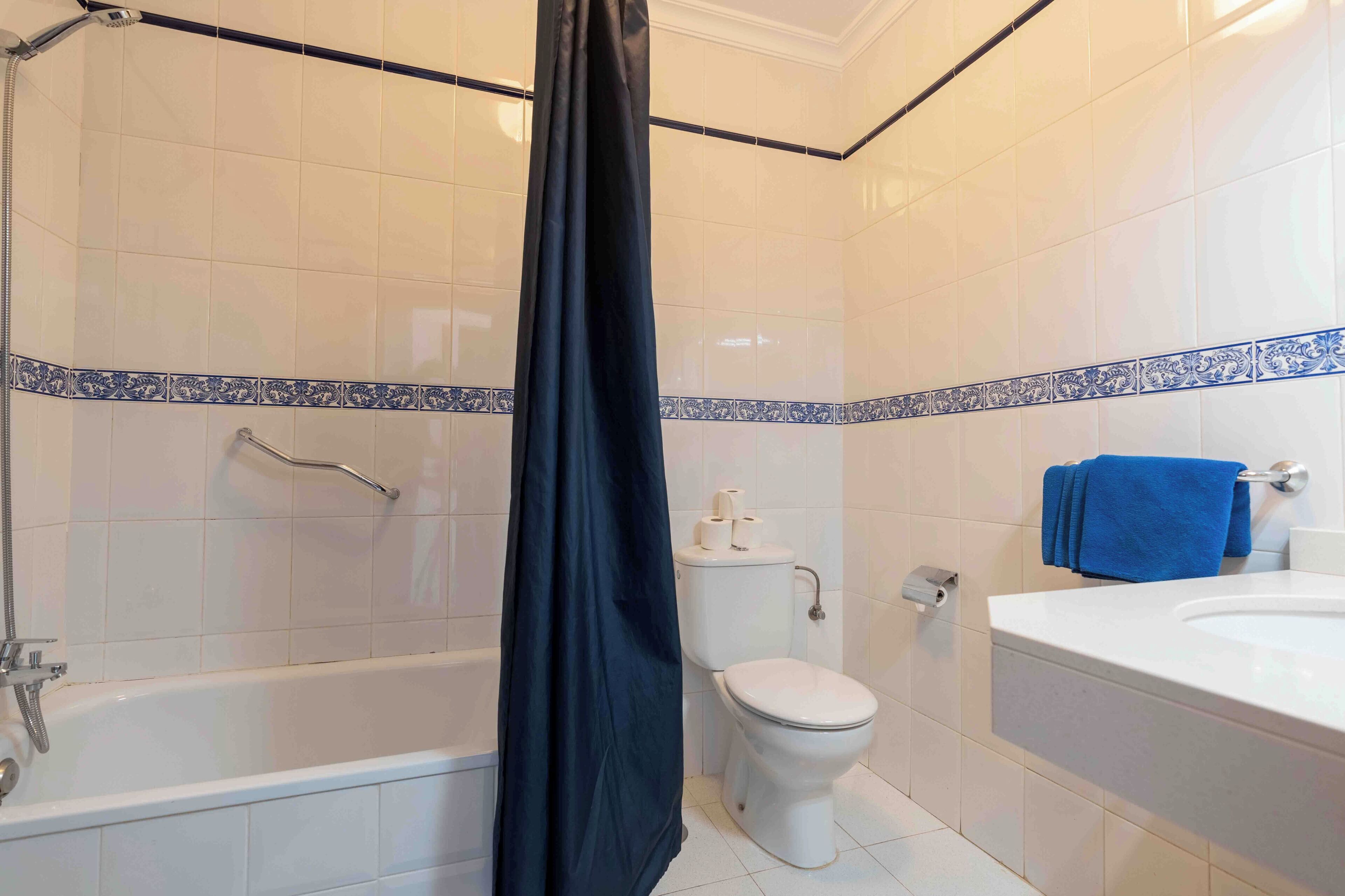 A bathroom with a bathtub, toilet, and shower curtain.