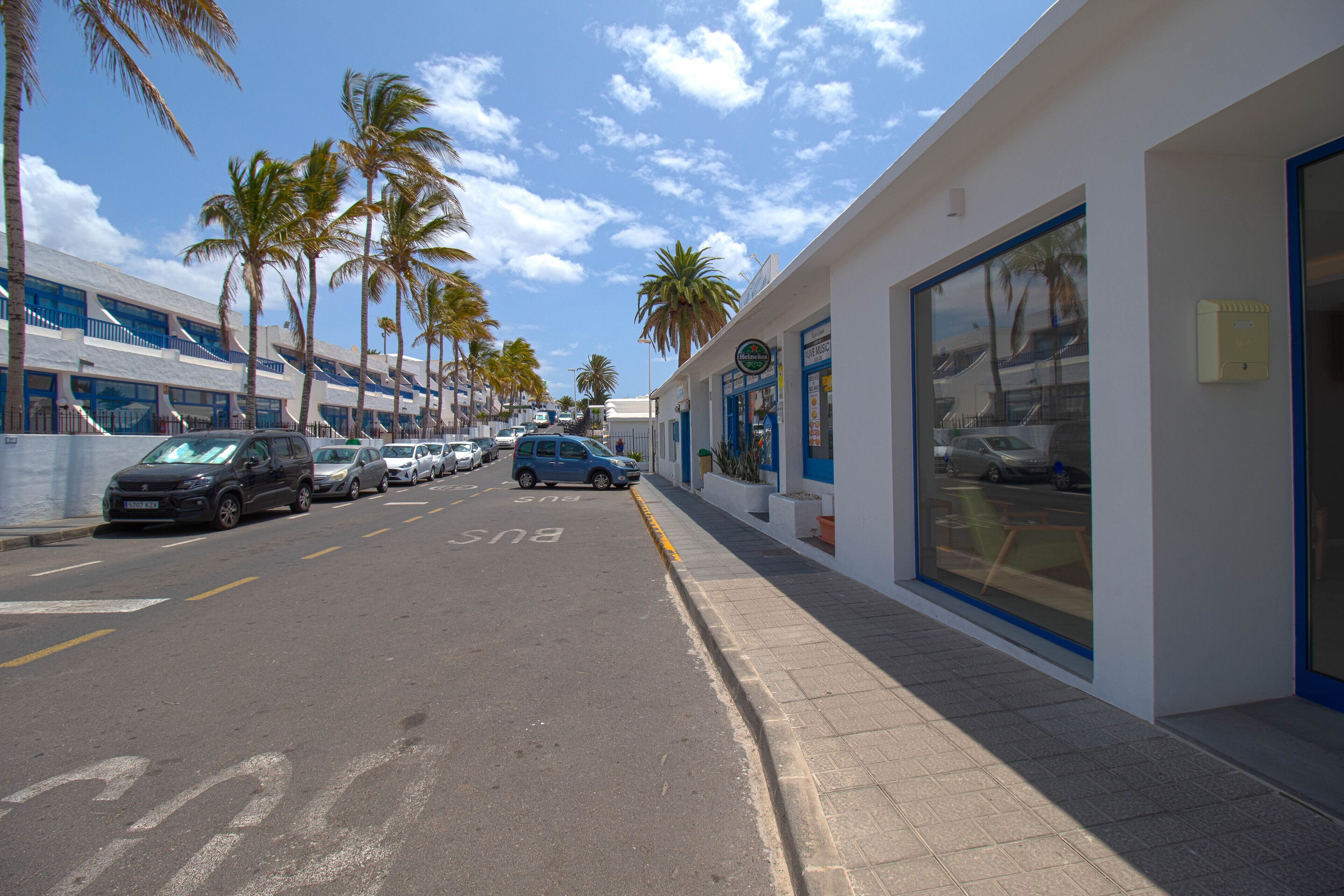 Una calle con coches aparcados y palmeras.