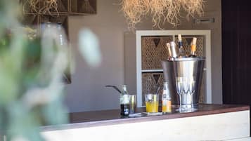 A bar area with a woven light fixture, a minibar, and two stools.