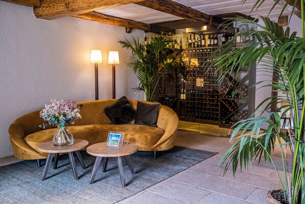 A cozy lounge area with a curved sofa, two round tables, and a potted plant. - Mas Sola (Santa Coloma de Farners)