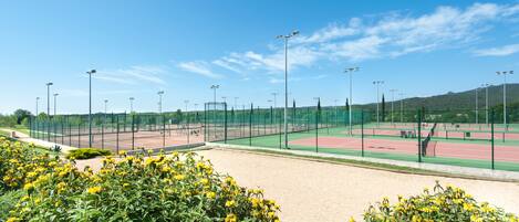 Un complexe sportif doté d’un court de tennis, entouré d’une clôture et équipé de projecteurs.