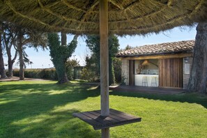 A patio with a wooden table and a thatched roof. - Mas Sola (Santa Coloma de Farners)