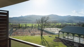 A view from a window overlooking a sports field with a pavilion, mountains in the distance, and a clear sky. - Mas Sola (Santa Coloma de Farners)