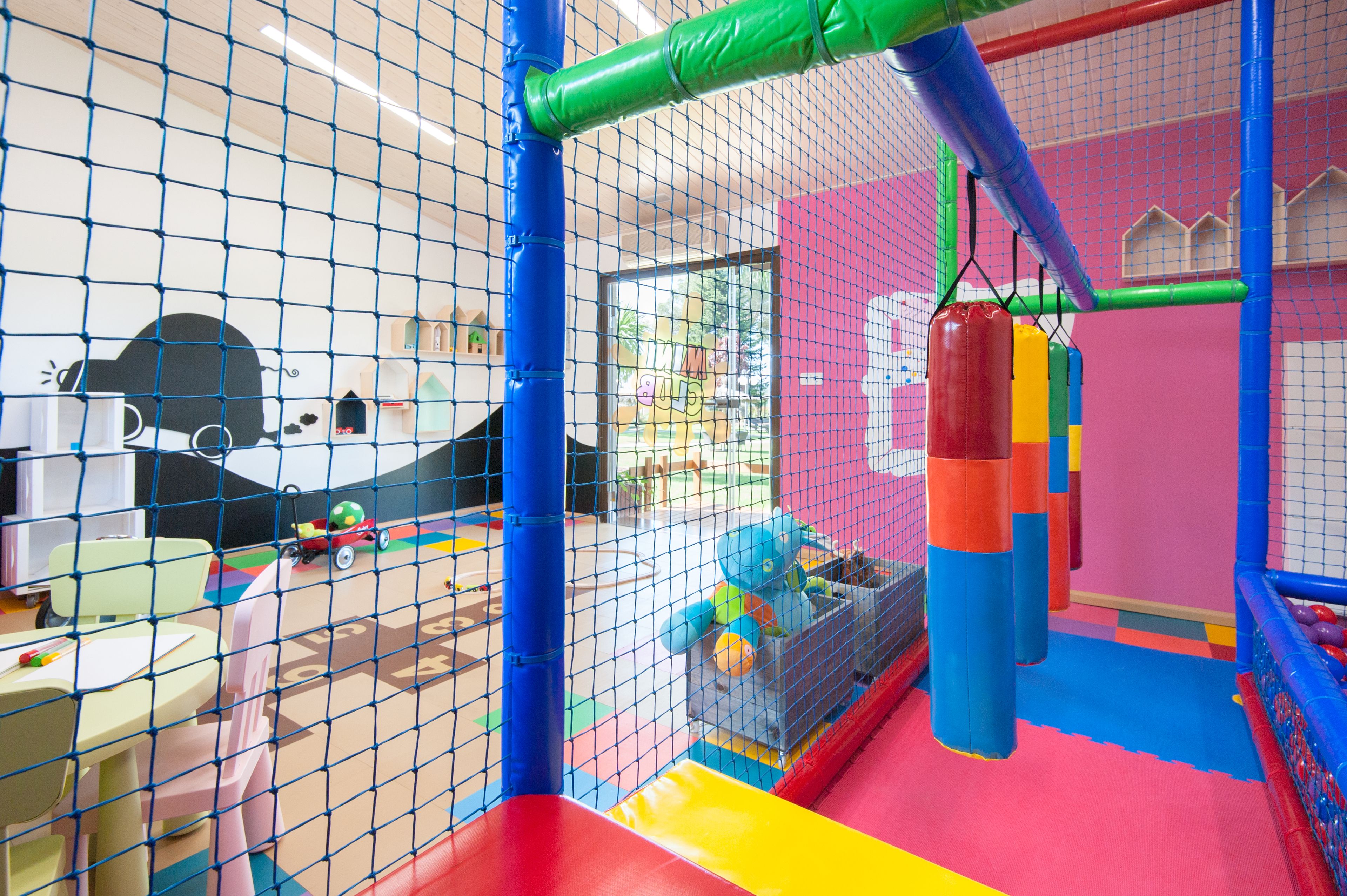 A children's play area with a netted enclosure, colorful play structures, and a slide.
