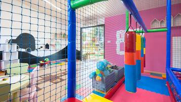 A children's play area with a netted enclosure, colorful play structures, and a slide.