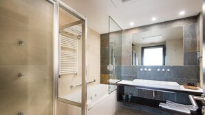 Ein modernes Badezimmer mit einer gläsernen Duschkabine, einer großen Badewanne und einem Waschtisch mit Spiegel.