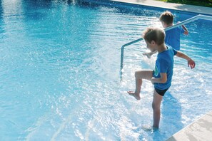 Une piscine à l’eau d’un bleu limpide, avec une échelle en métal.