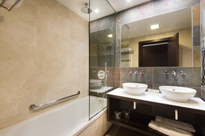 Un baño moderno con ducha envuelta en vidrio, bañera y dos lavamanos.