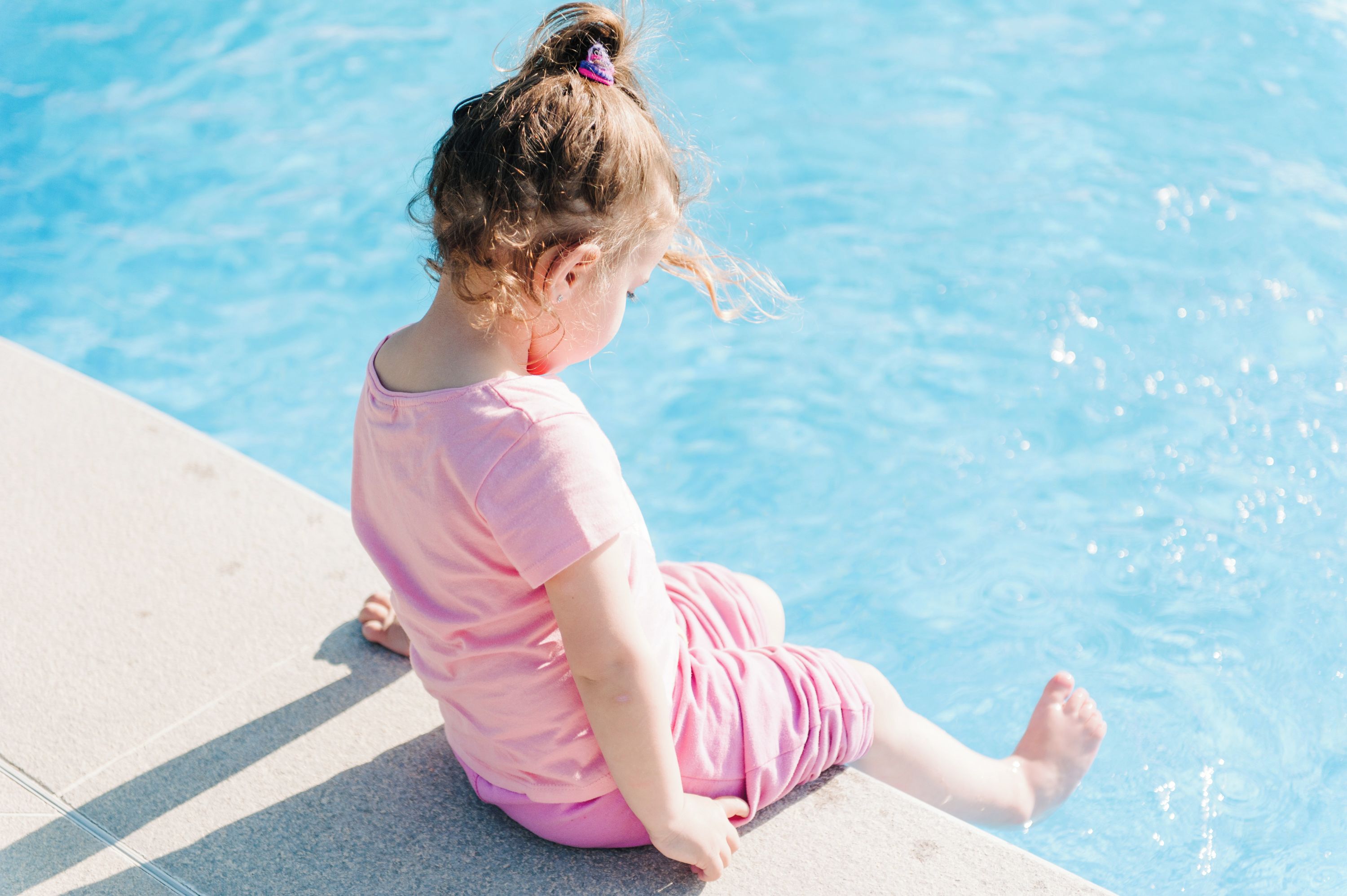 A child sitting by a poolside.