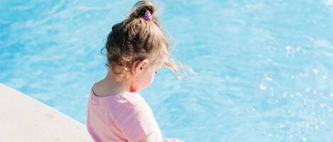 Ein Kind sitzt am Pool.