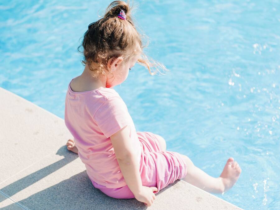 Ein Kind sitzt am Pool.