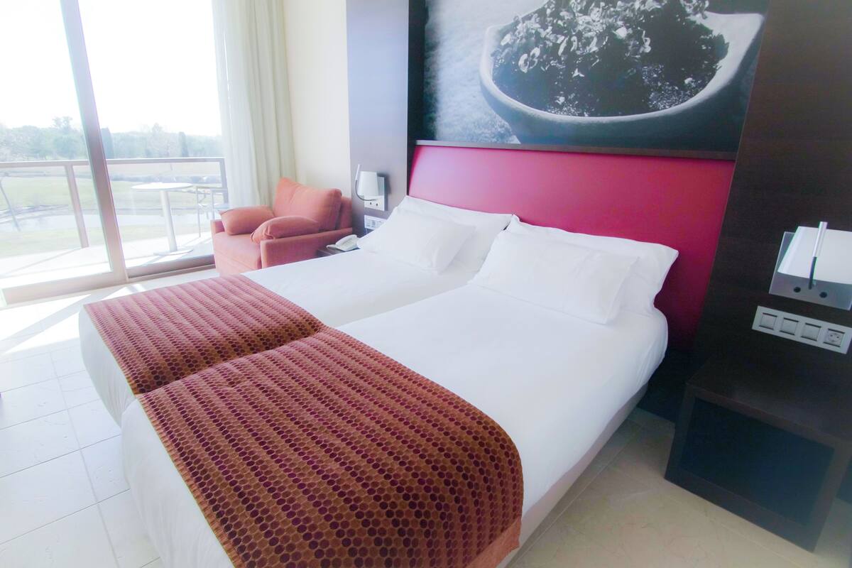 Une chambre d’hôtel avec un grand lit, une chaise, un bureau et une vue sur l’extérieur.