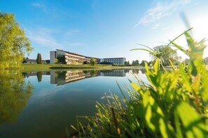 A modern building with a reflective pond in front, surrounded by greenery and clear skies. - Mas Sola (Santa Coloma de Farners)