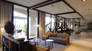 Eine moderne Hotelhalle mit großzügiger Sitzecke, einer Bücherwand und einer dekorativen Skulptur.