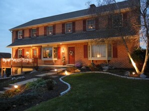 A two-story brick house with a front porch, a Christmas tree, and a well-maintained lawn. - Homestead Lodging (Lancaster)
