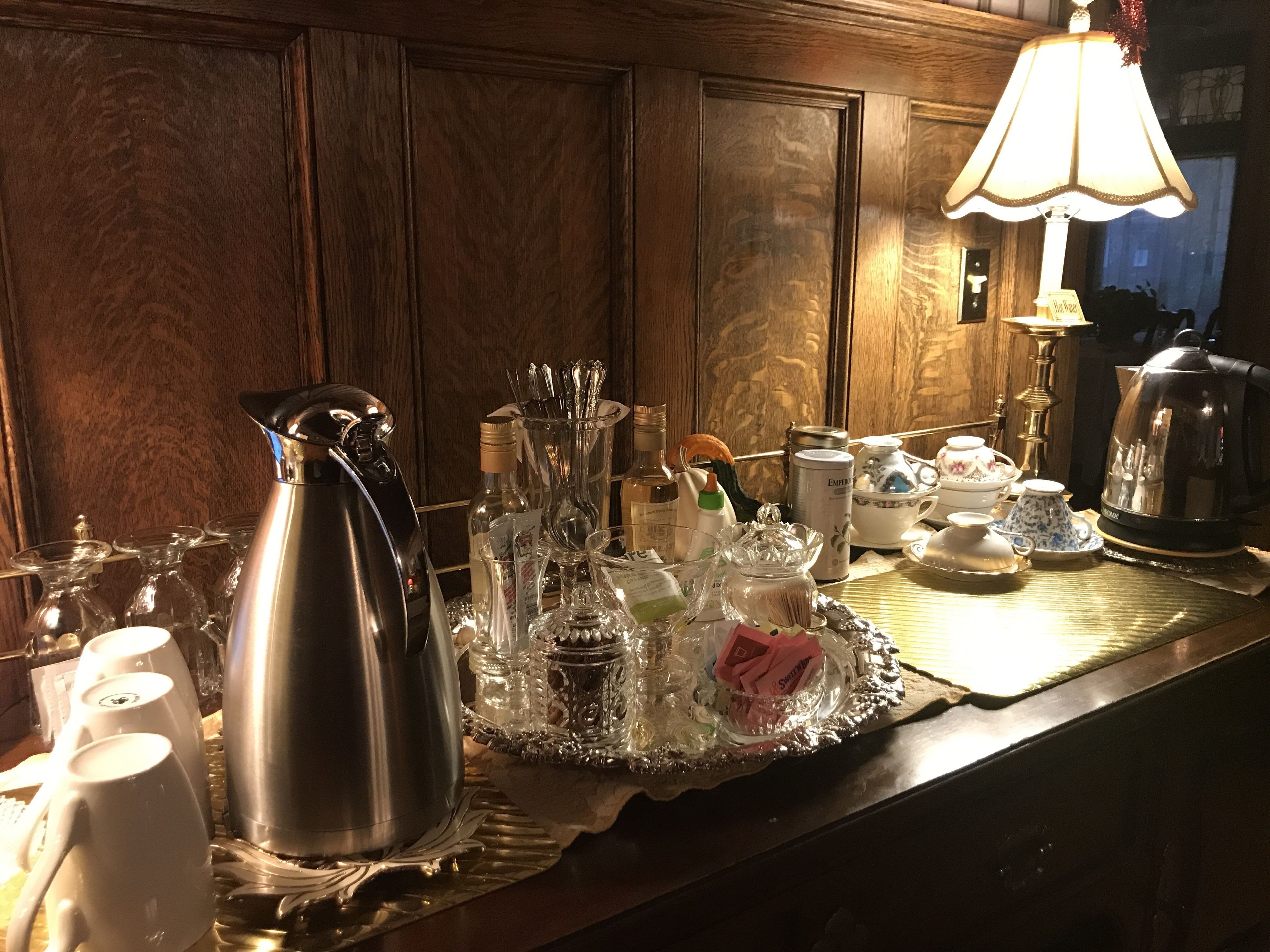 A bar area with a coffee pot, glasses, and various bottles.