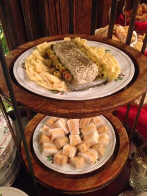 A three-tiered serving tray with a fish fillet, pasta, and bread cubes. - Brass Pineapple Inn (Charleston)