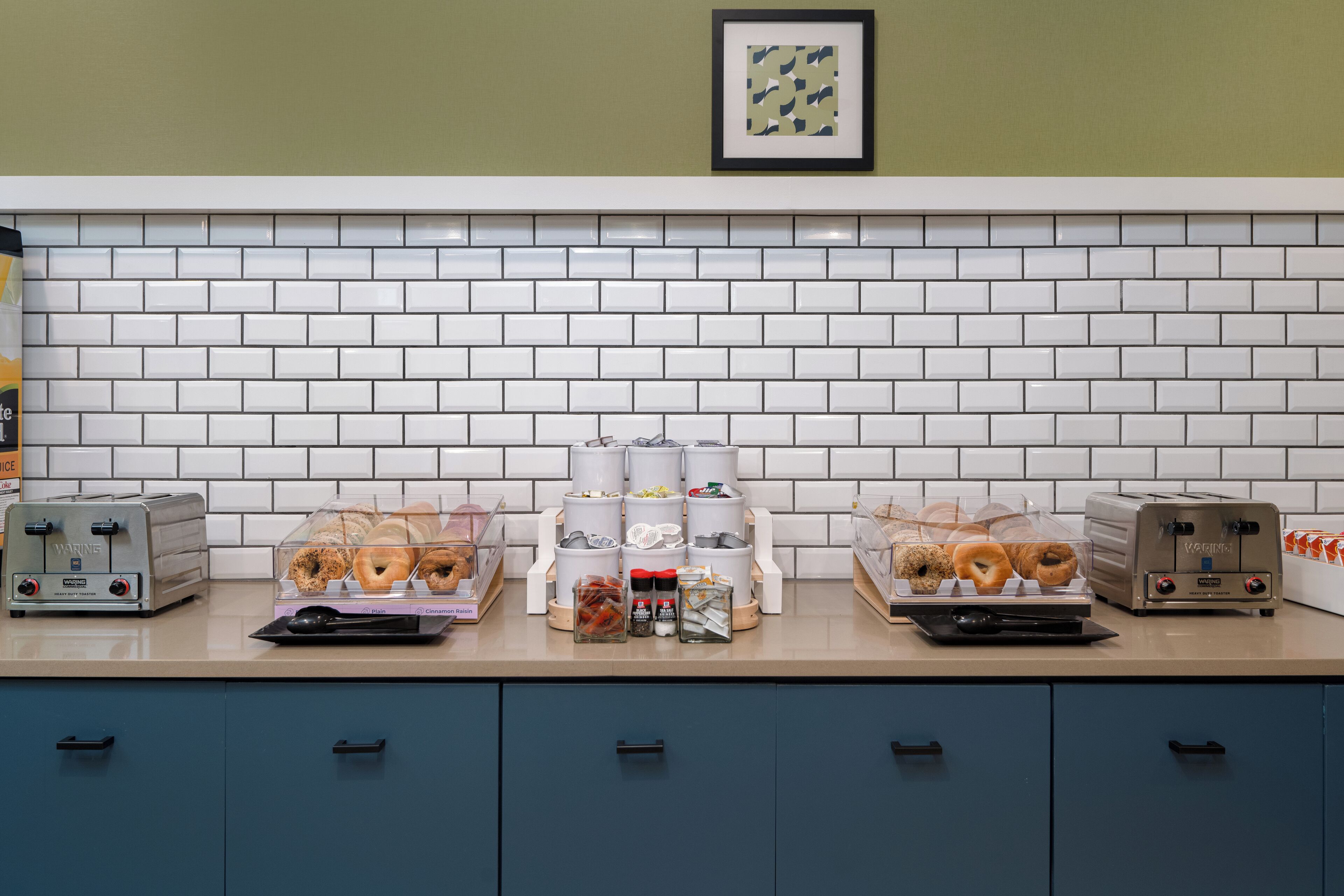 A breakfast bar with toasters, a coffee station, and a display of pastries.