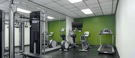 A gym with various exercise equipment, including a bench press, a squat rack, and treadmills.