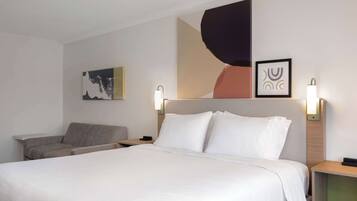 Een hotelkamer met een groot bed, een stoel en twee wandlampen.