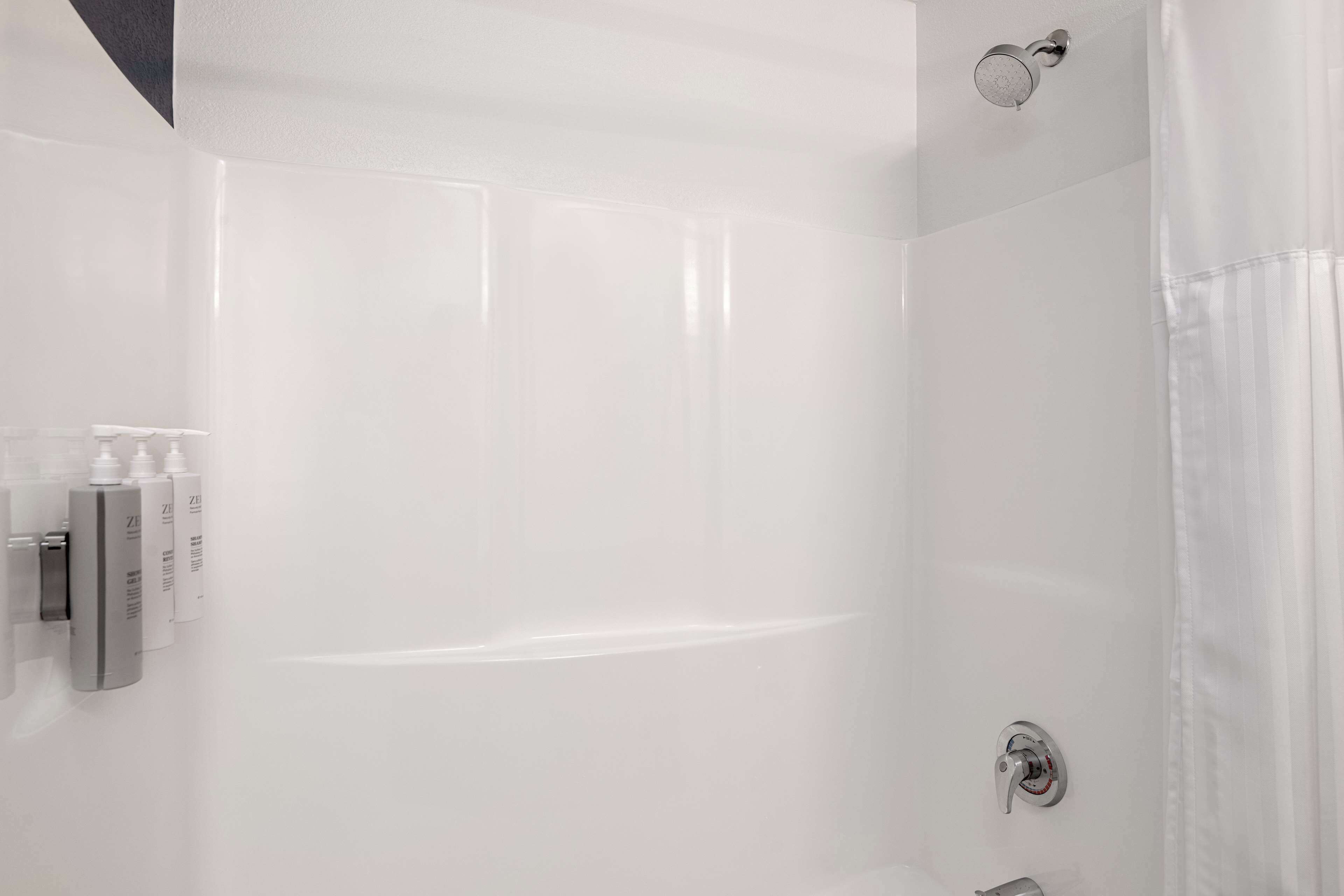 Un baño moderno con cabina de ducha de vidrio, ducha de mano y grifo empotrado.