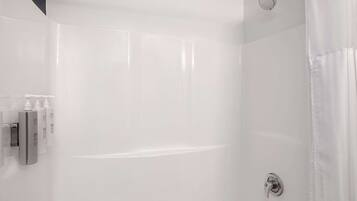 Un baño moderno con cabina de ducha de vidrio, ducha de mano y grifo empotrado.