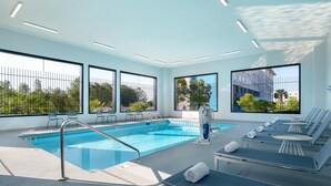 Une piscine intérieure moderne avec des parois en verre transparent, des espaces de détente baignés de lumière et une vue sur la verdure environnante.