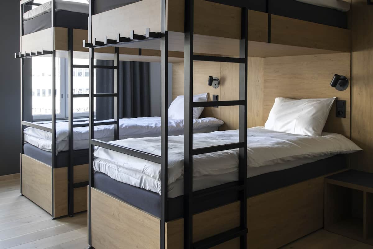 Une chambre moderne avec des lits superposés, un plancher en bois et une fenêtre laissant entrer la lumière naturelle.