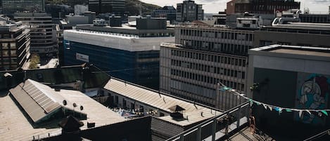 A rooftop terrace with a view of surrounding buildings, including a modern glass skyscraper and a mix of older structures.