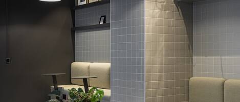 A modern reception area with a wooden reception desk, grey cushioned seating, and a small plant.