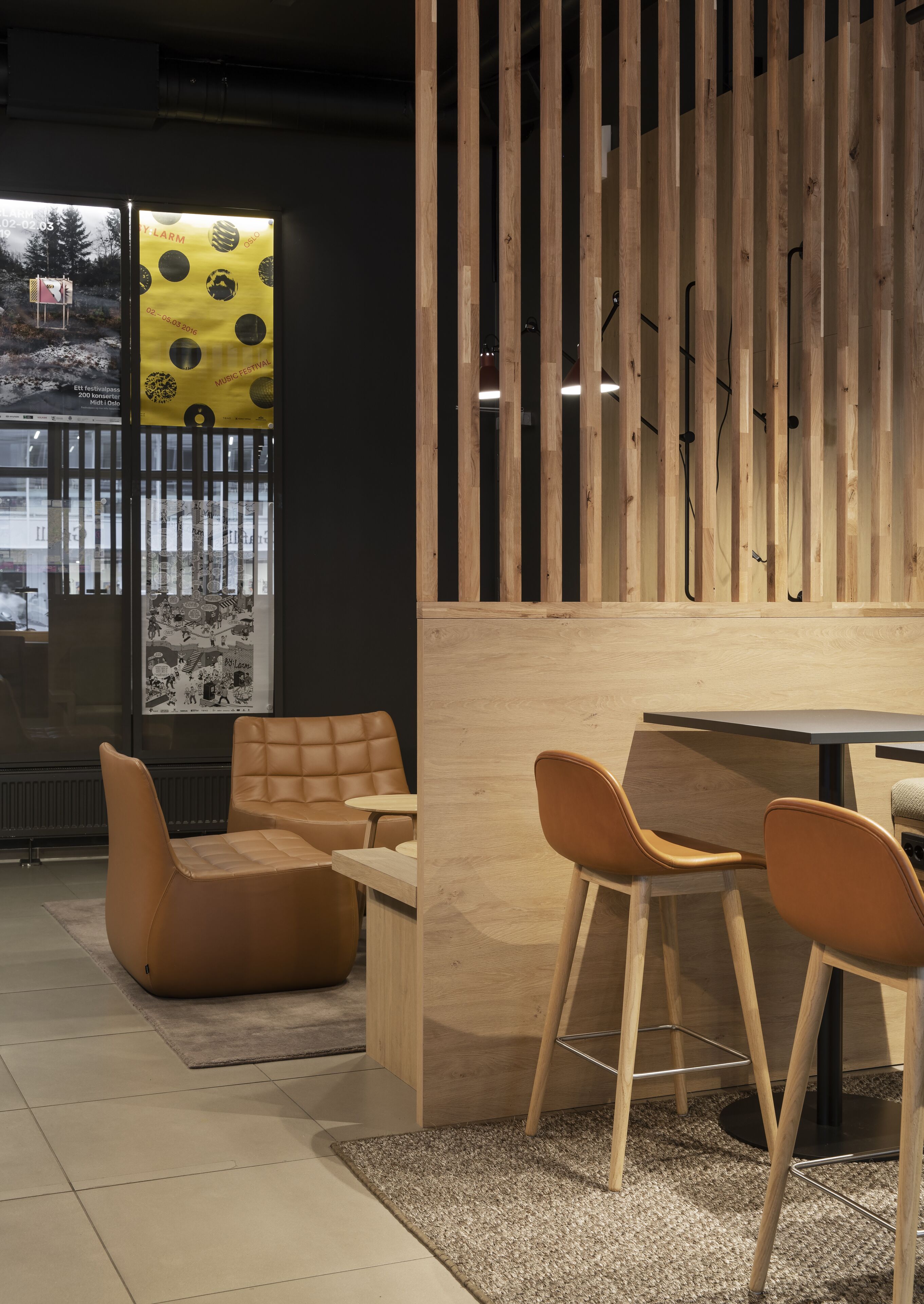 A modern interior with a wooden partition, a sofa, two chairs, and a table.