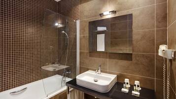 Un baño moderno con ducha envuelta en vidrio, un lavabo blanco y un espejo sobre el lavabo.