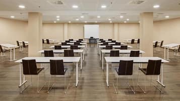 A conference room with multiple tables and chairs, a whiteboard, and a projector screen.